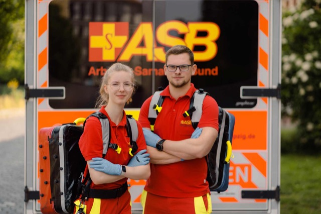 Zwei Notfallsanitäter des ASB mit Rucksäcken vor dem Einsatzfahrzeug