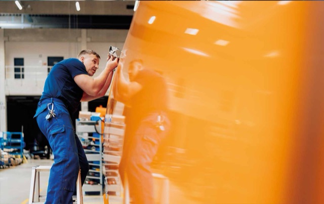 FAUN-Mitarbeiter in der Halle neben einem orangefarbenen Aufbau