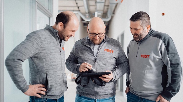 Drei Mitarbeiter der FEST GmbH besprechen ein Projekt am Tablet