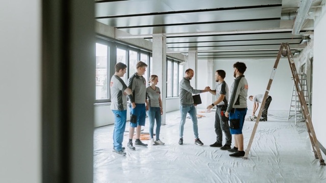 Team der FEST GmbH in einem hellen Rohbau mit Leitern