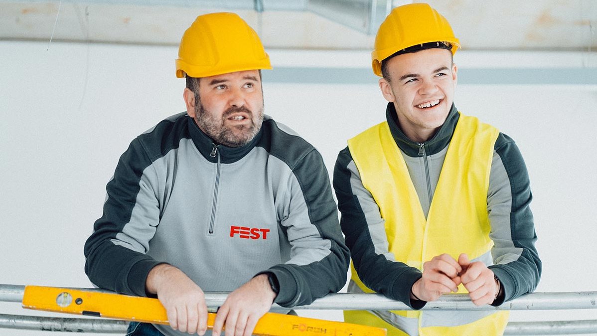 Zwei Elektriker der FEST GmbH mit Helm auf der Baustelle
