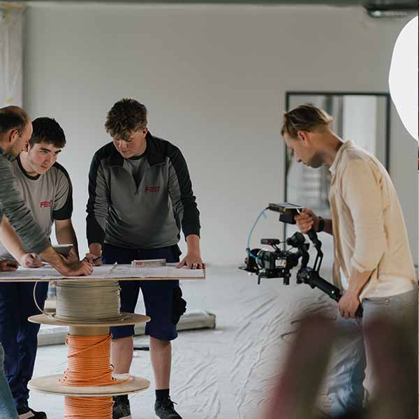 Azubis der FEST GmbH am Bauplan, David Rieger filmt sie mit der Kamera