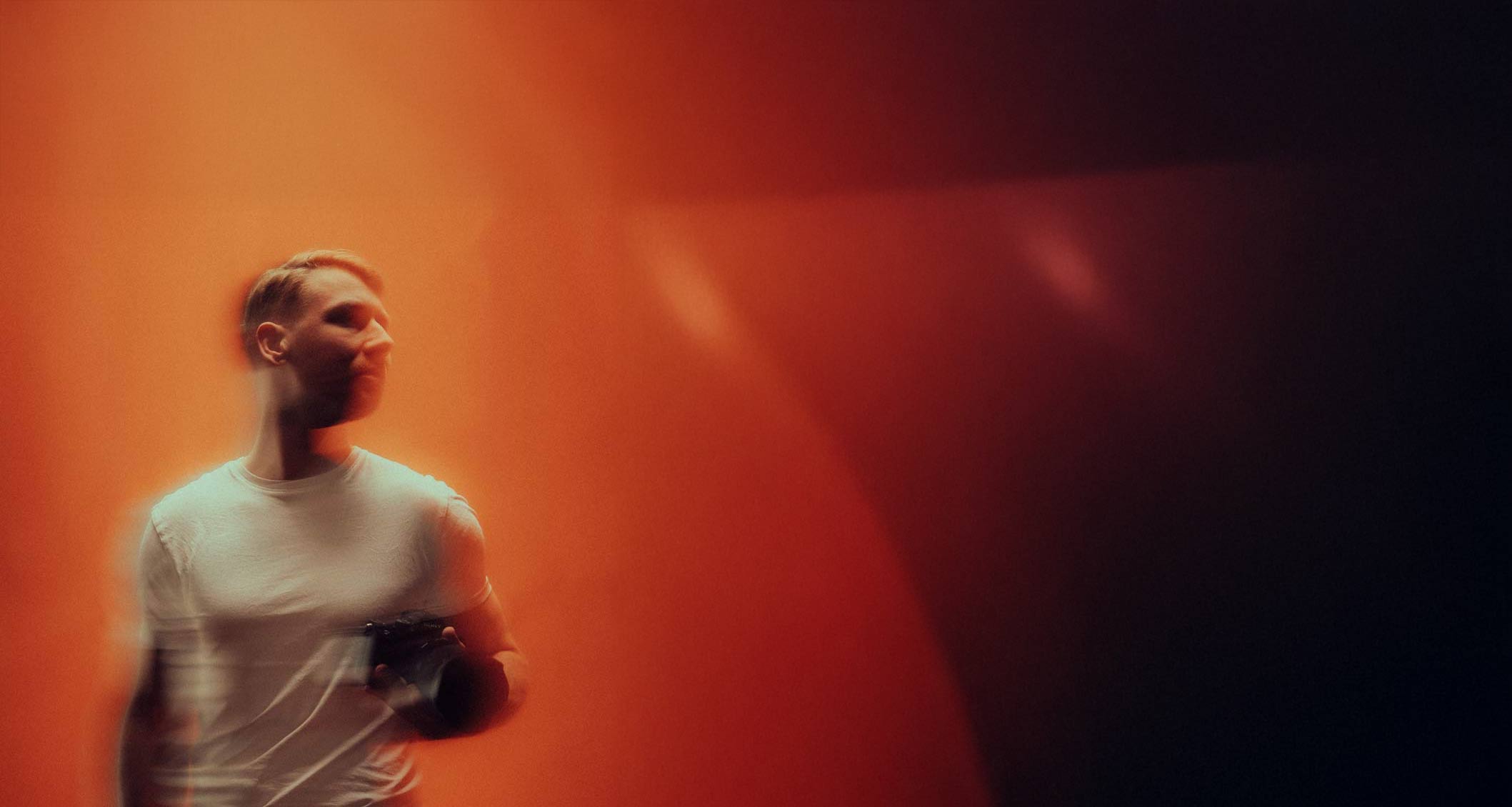 David Rieger mit Kamera in orangem Licht