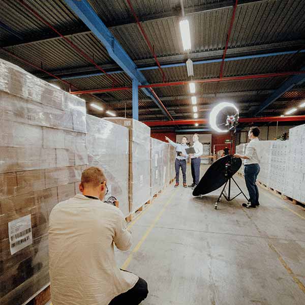 Drehtag in der Lagerhalle: zwei Mitarbeiter werden zwischen Paletten gefilmt