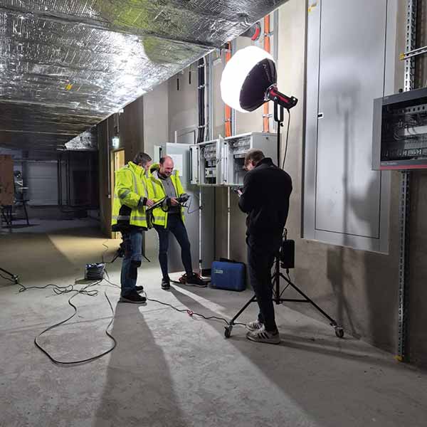 Drehtag im Technikraum: zwei Elektriker am Schaltschrank werden gefilmt