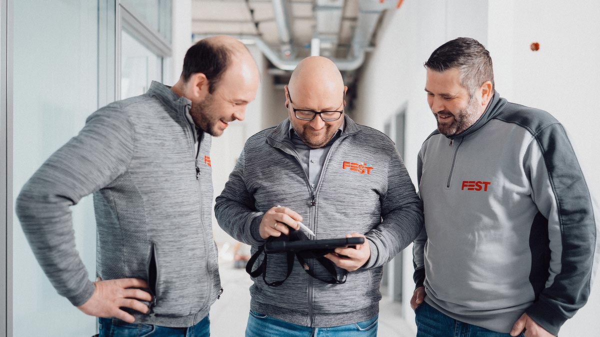 Drei Mitarbeiter der FEST GmbH besprechen etwas am Tablet