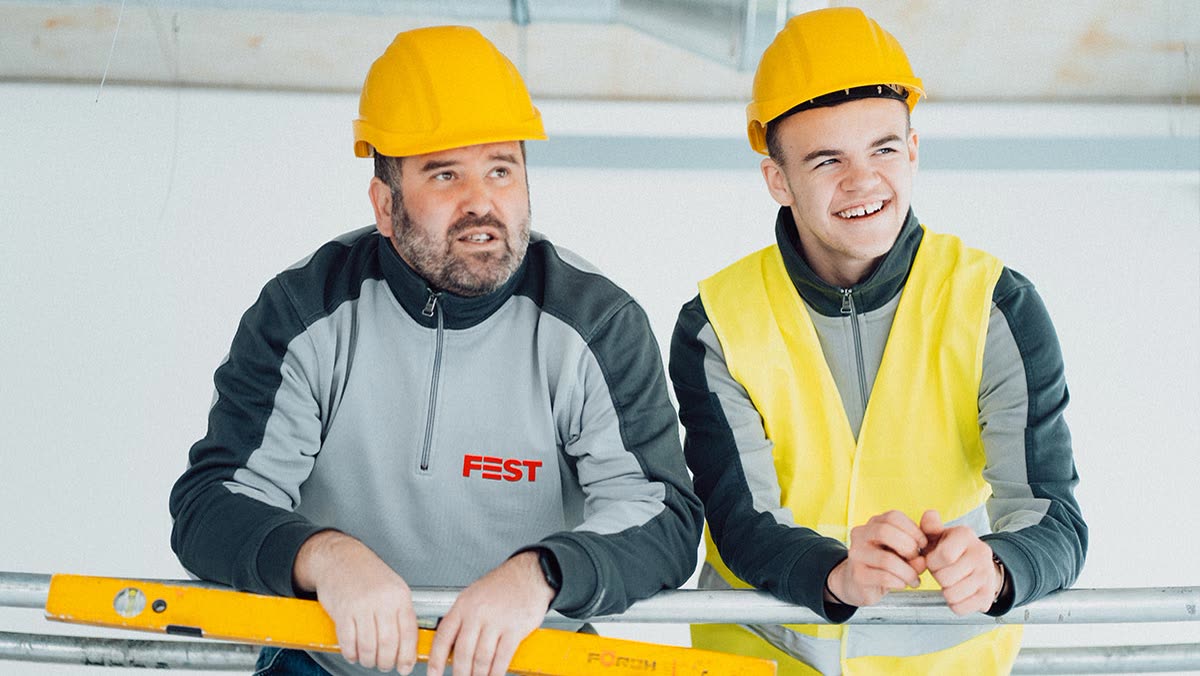 Meister und Azubi der FEST GmbH mit Bauhelm