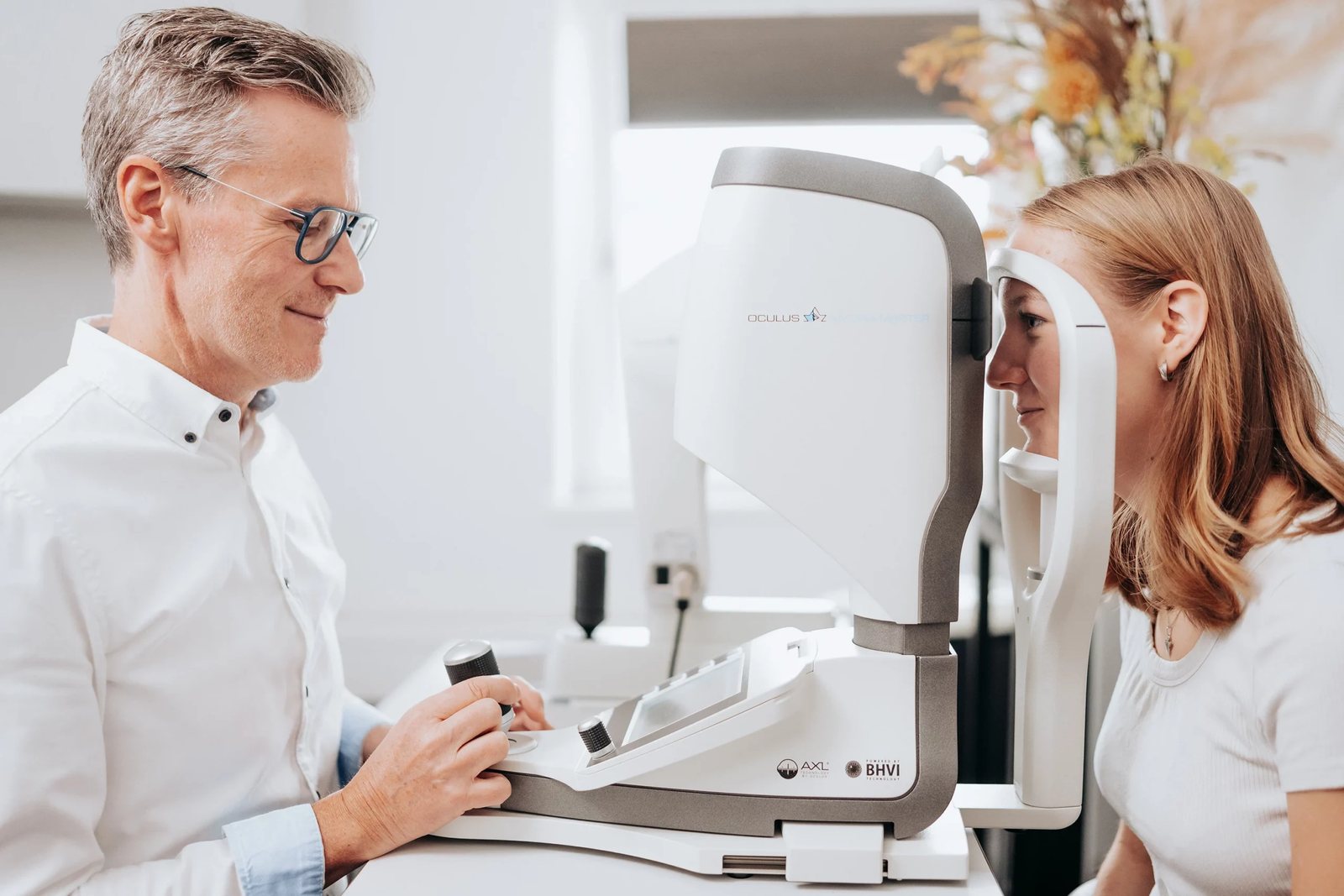 Augenoptiker prüft die Augen einer jungen Frau am Messgerät