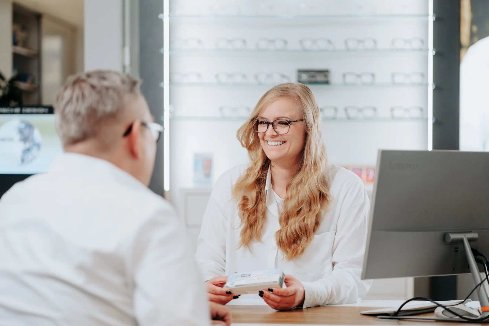 Mitarbeiterin von Augenoptik Findeisen berät einen Kunden am Tisch