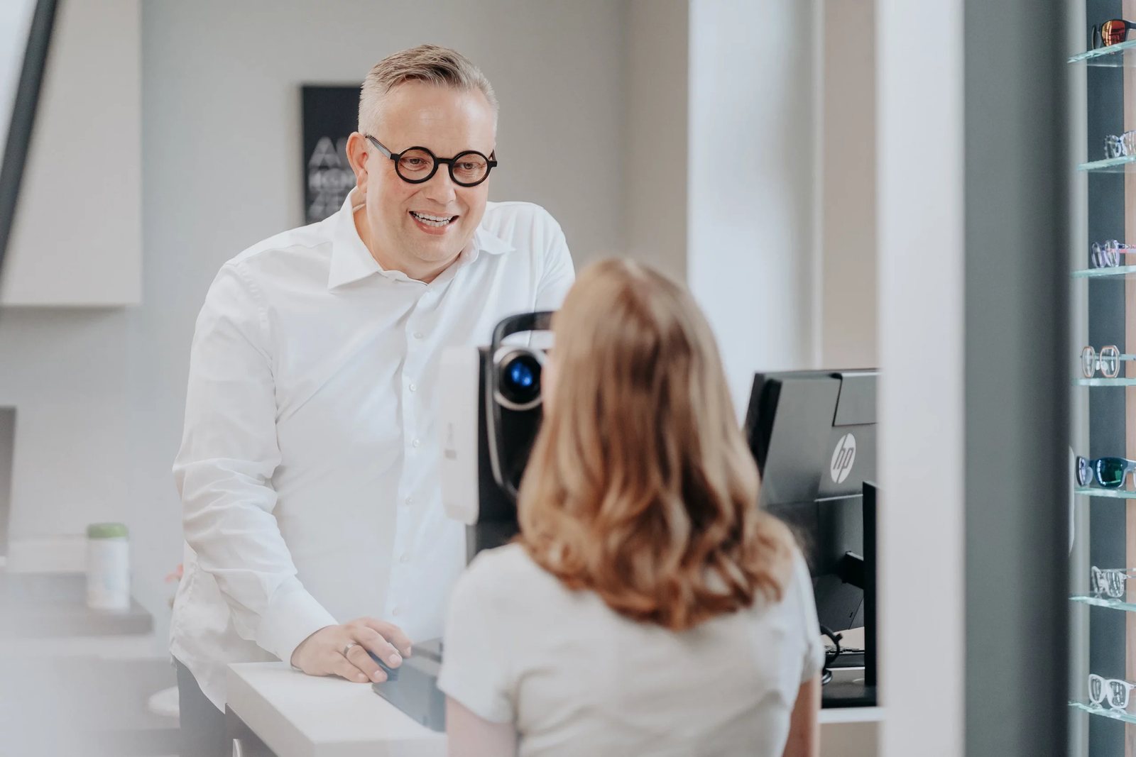 Augenoptiker misst bei einer Kundin die Sehwerte am Messgerät