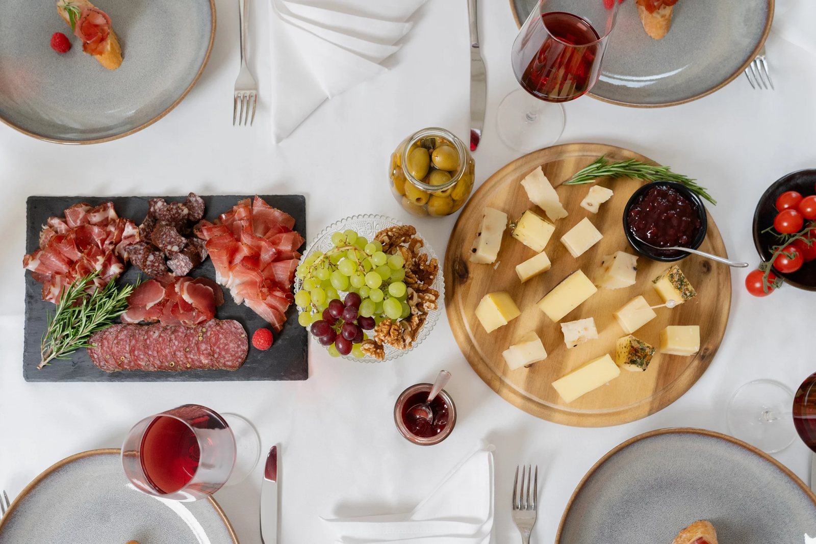 Gedeckter Tisch von oben mit Schinken, Käse, Trauben und Rotwein