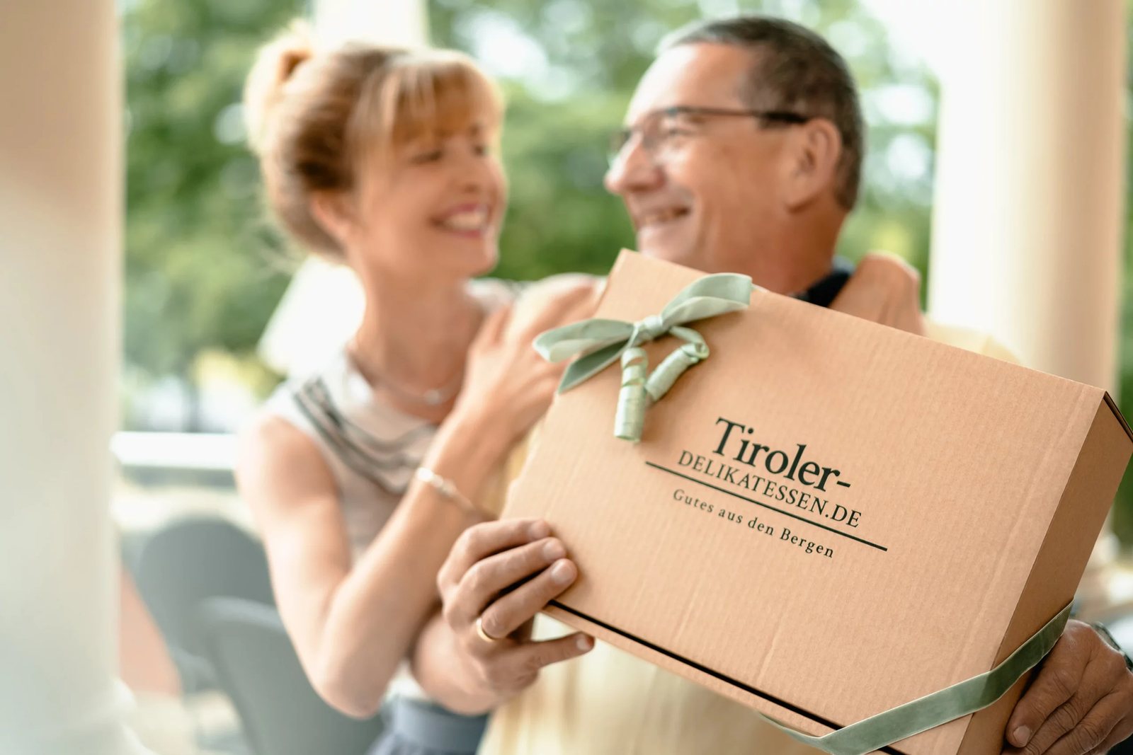 Mann überreicht einer Frau eine Geschenkbox von Tiroler Delikatessen