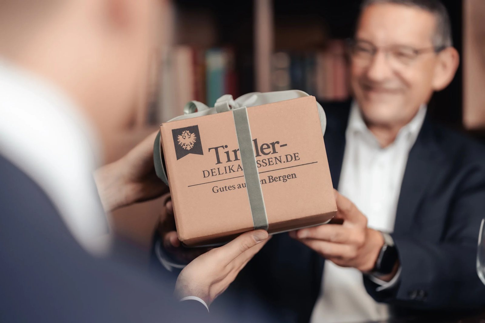 Geschenkbox von Tiroler Delikatessen wird an einen Geschäftsmann überreicht