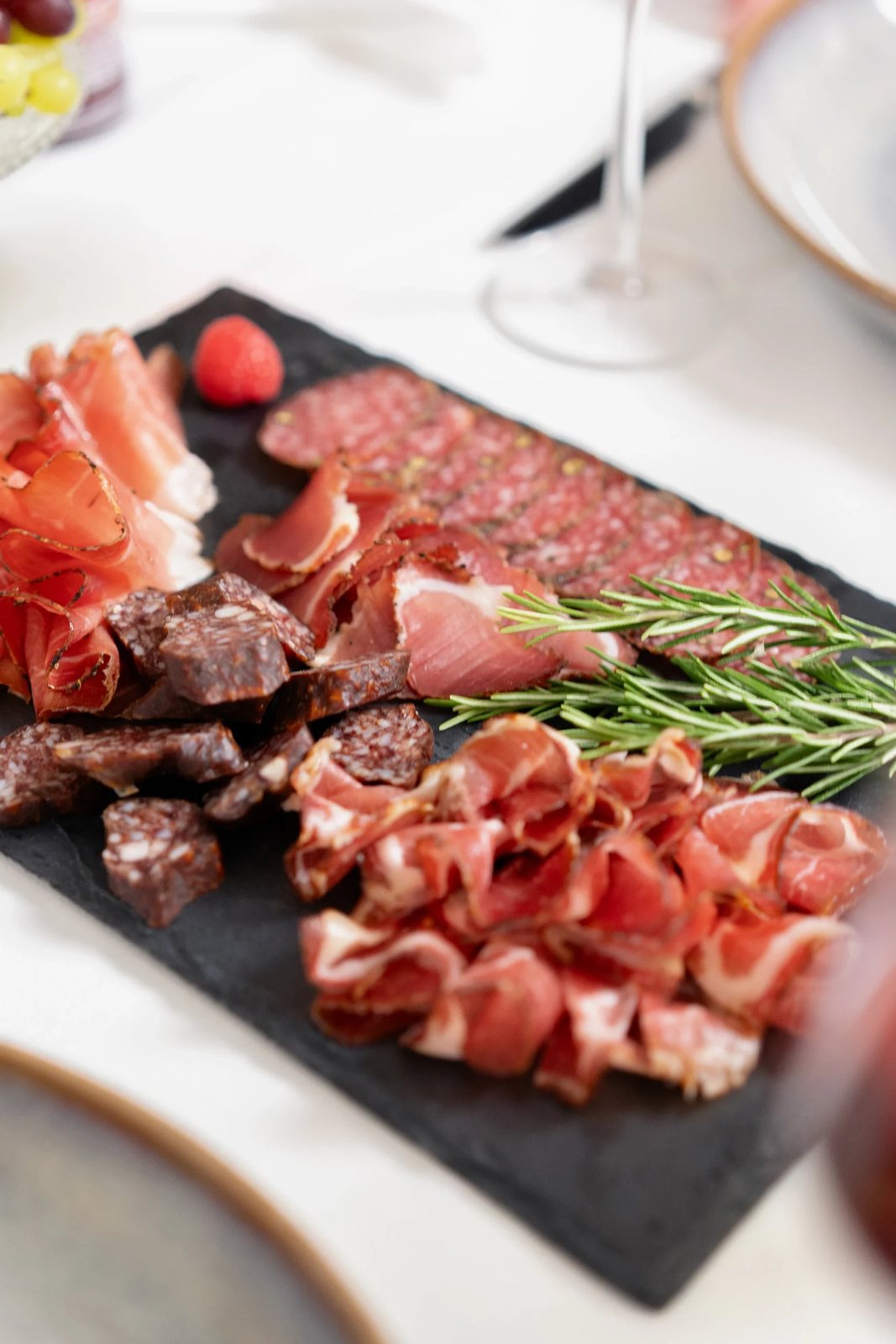 Schieferplatte mit Schinken- und Wurstspezialitäten auf dem gedeckten Tisch